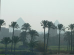 Пирамиды сквозь смог города.