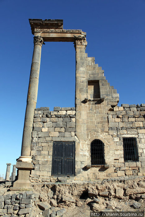 Колонна у каменной стены Босра, Сирия