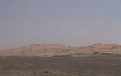 Эрг Шебби издалека. На переднем плане видна обычная каменистая пустыня, окружающая его со всех сторон