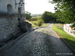 Неровная брусчатая дорожка и рядом с ней тротуар из неровно уложенных каменных плит вели к воротам замка.