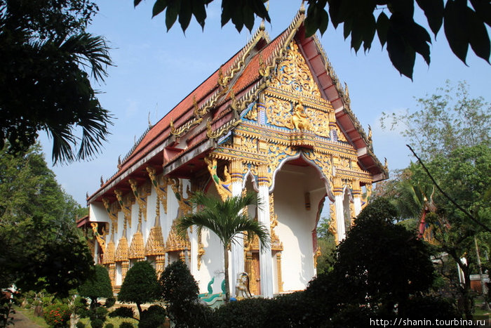 Типичный тайский храм — белый, с красной псевдочерепичной крышей (черепицы не глиняные, а металлические или пластмассовые) и позолотой. Трат, Таиланд