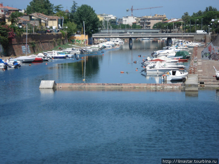 недалеко от моста расположились разные рыбацкие лодки и катера Римини, Италия