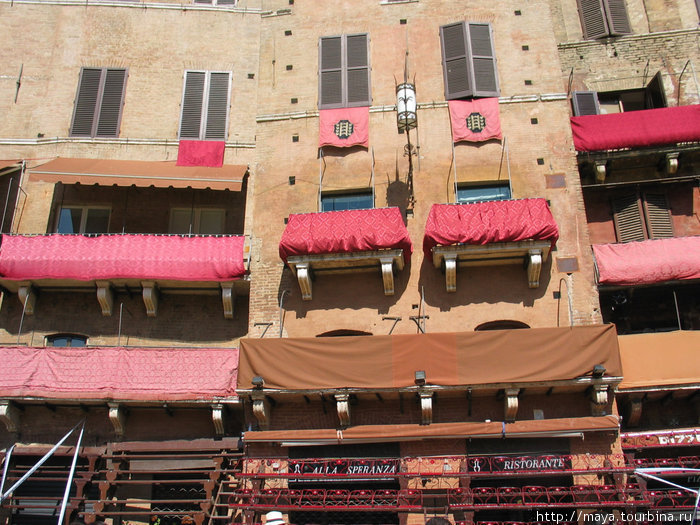Трибуны уже установлены, балконы и окна обтянуты тканями цвета контрад Сиена, Италия