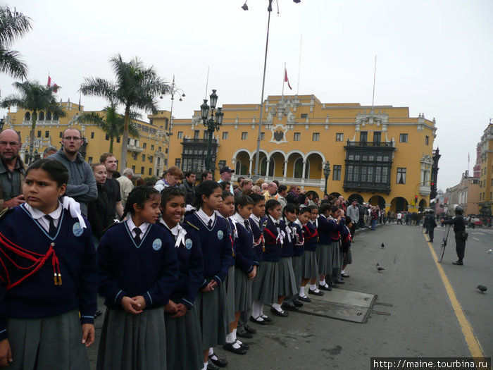 Школьники и туристы через дорогу наблюдают за тасовками караула в президентском дворце.