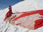 Инструктор расправляет крыло на крутом склоне горы