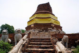 Празднично украшенная полуразрушенная кирпичная ступа в монастыре Ват Туммикарат