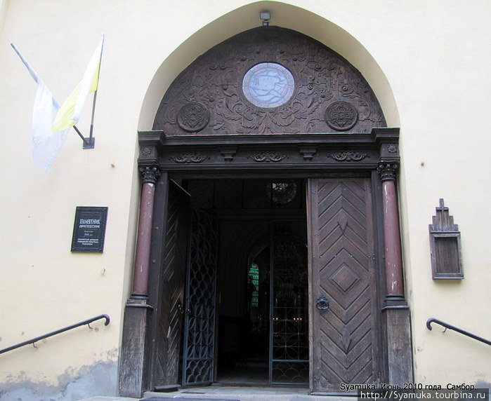 Массивная дверь с полуколоннами и красивым резным деревянным сводом является главным входом в костел. Самбор, Украина