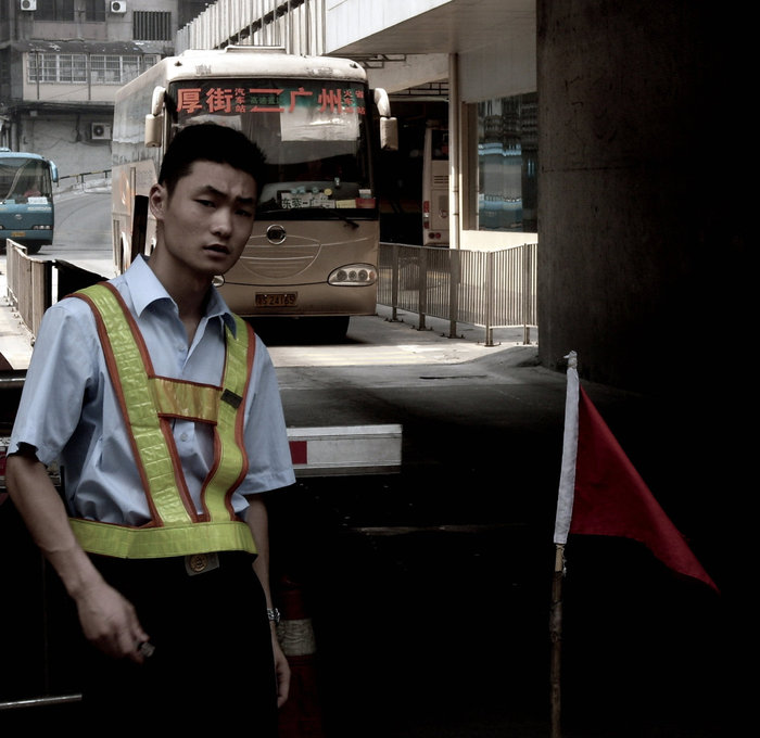 Регулировщик на выезде из автобусной станции. За раз может следовать колона из 10 атобусов. Гуанчжоу, Китай