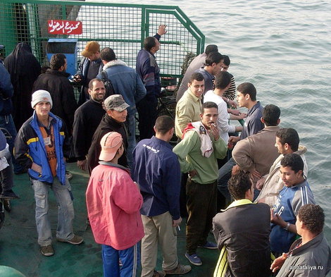 Египетские мужчины плывут на пароме через Суэцкий канал в Порт-Саиде