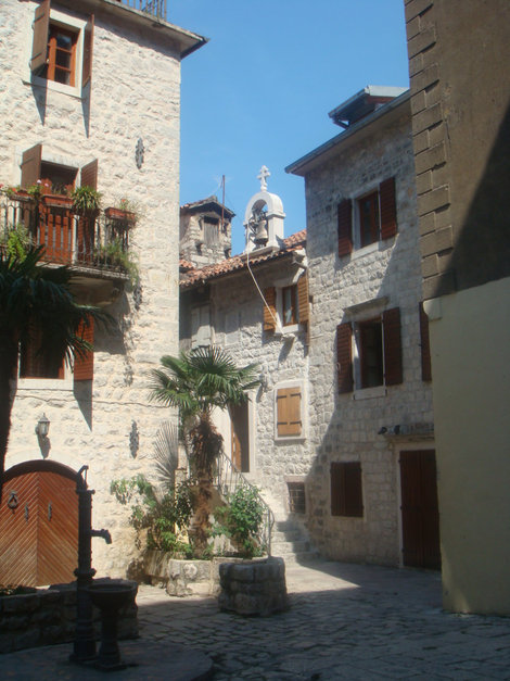 Которский дворик с церковным колоколом и колонкой на первом плане слева Будва, Черногория