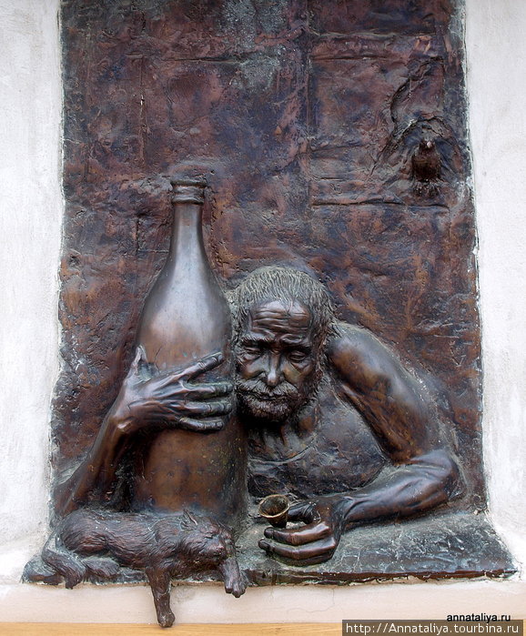 В центре рядом с главной площадью на стене одного из кафе — пьяница с рюмкой в одной руке, с бутылкой в другой и со спящей рядом кисой, видимо, утомленной винными парами, исходящими от хозяина. Вильнюс, Литва