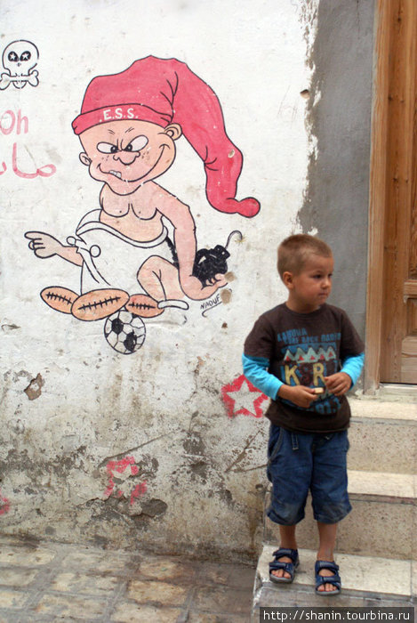 Ребенок и детский рисунок на стене дома в медине Сусс, Тунис