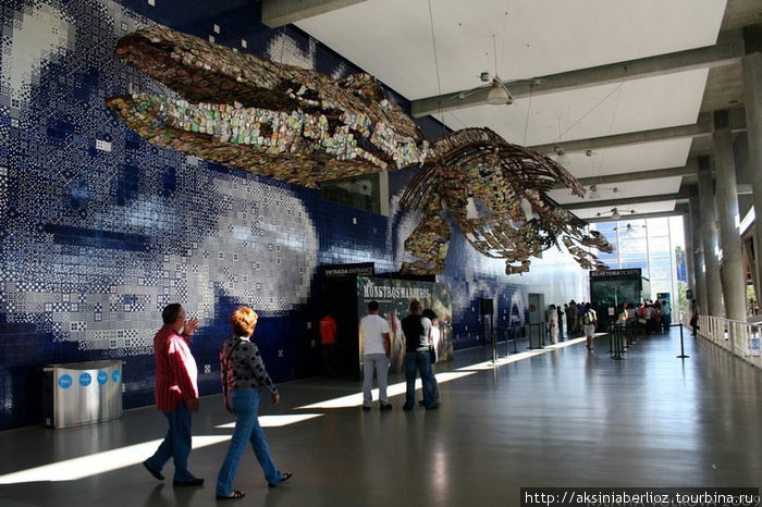 Огромный динозавр из сплюснутых жестяных банок из-под кока-колы и пива приветствует посетителей прямо в холле у касс Лиссабон, Португалия