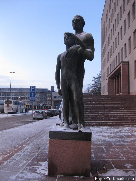 Отец наставляет сына — оба, по-видимому, вышли из городской ратуши, что на заднем плане Котка, Финляндия