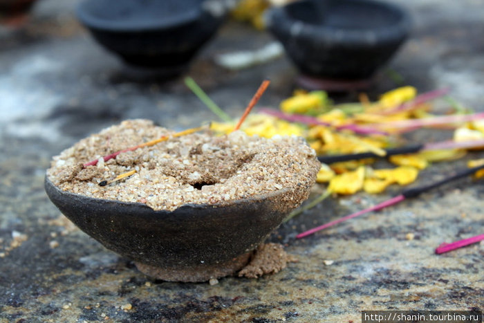 Ароматные палочки и глиняные чаши для жертвоприношений перед изображением Будды Полоннарува, Шри-Ланка