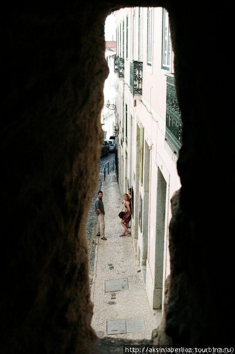 Вид на соседнюю улицу через пробоину в старой стене. Лиссабон, Португалия
