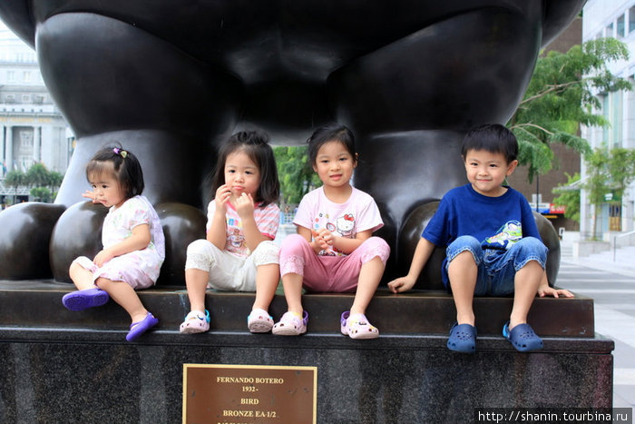 Дети позируют на фоне памятника Сингапур (город-государство)