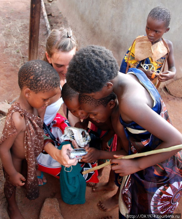 туристка из Аргентины показывает детям их фото Округ Хохо, Свазиленд