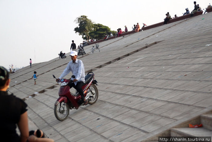 Мотоциклист спускается по набережной к воде Пномпень, Камбоджа