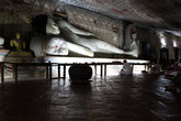 Монах и лежащий Будда в темноте пещеры