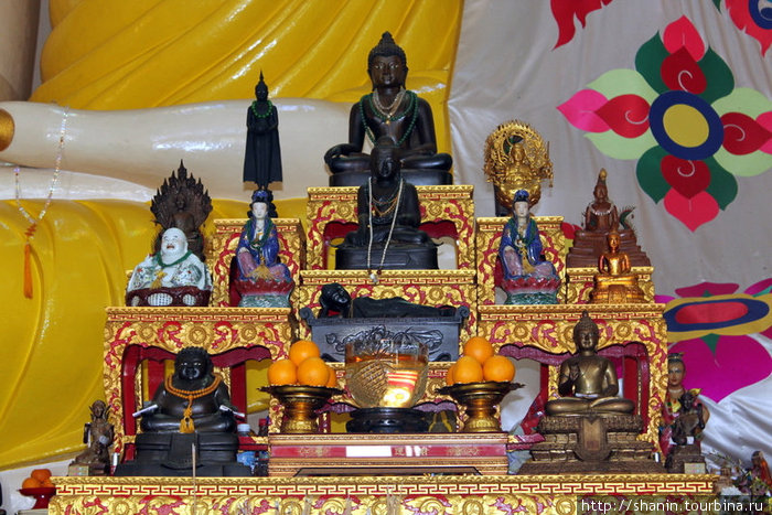 Алтарь со статуэтками богов у ног сидящего Будды Сингапур (город-государство)