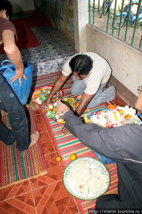 Прихожане разбирают пожертвованную монахам и невостребованную ими пищу Удон-Тани, Таиланд