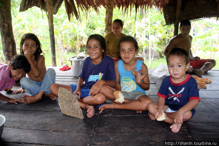 Семья на деревянном полу под соломенной крышей Остров Уполу, Самоа