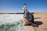 На заднем плане малая часть дамбы, которая отделяет казахскую часть Арала от узбекской. Уровень воды регулируется водосбросом, сразу за которым и располагаются рыбаки.