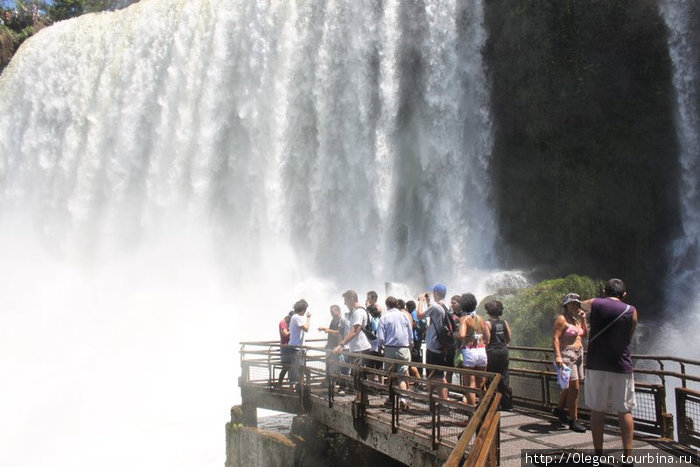 Люди подходят к водопадам поближе, чтоб насладиться брызгами- это спасает от жары Пуэрто-Игуасу, Аргентина