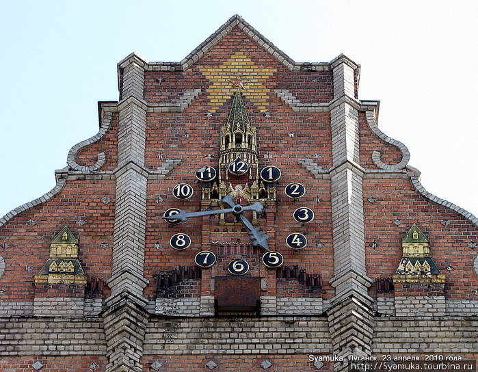 На короне фасада здания — пятиконечная стилизованная кирпичная звезда с часами на Спасской башне, по бокам – силуэты кремлевских башен. Луганск, Украина