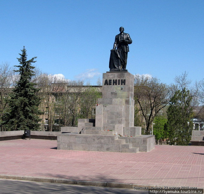 Слева — площадь Революции, на которой возвышается памятник ее вождю В. И. Ленину. У подножия памятника — живые цветы. Луганск, Украина