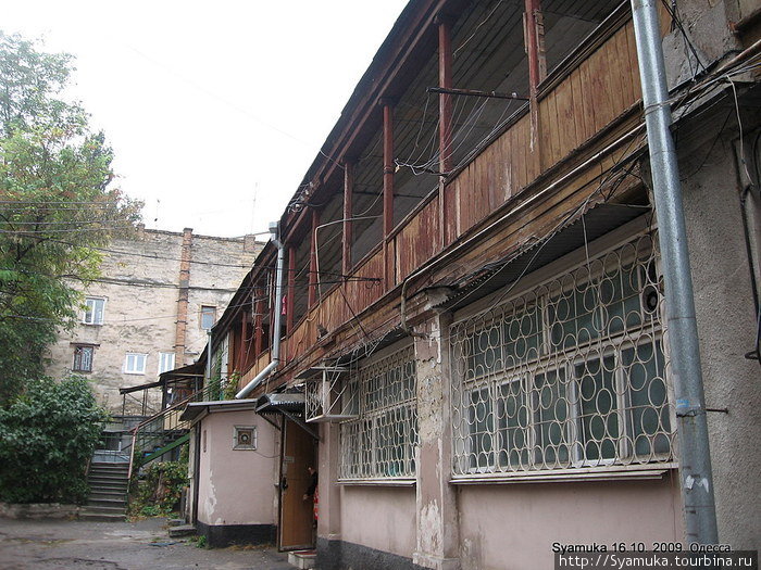 На окнах затейливые решетки, деревянная дверь с козырьком и киской на карнизе над кондиционером...и...веревки... веревки... шнуры... трубы... опять веревки... Одесса, Украина