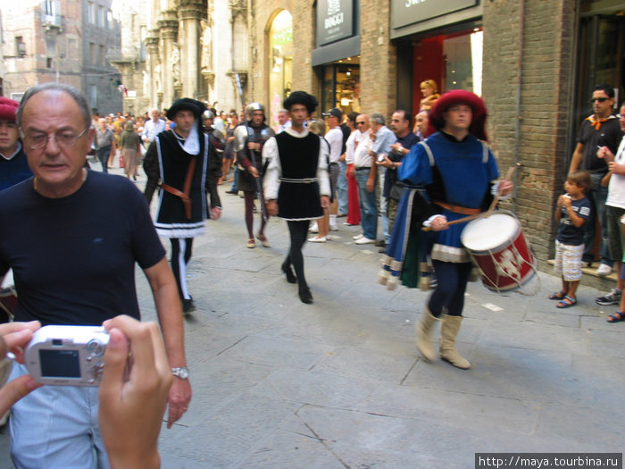 за ними участники парада Сиена, Италия