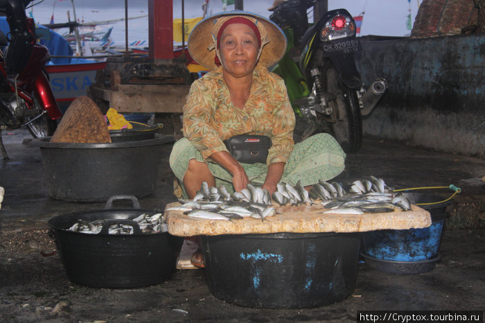Женщина торгует мелкой рыбешкой, которую собирает рано утром в полосе прибоя Джимбаран, Индонезия