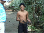 Мальчик индеец майя показывает туристам летучую мышь.