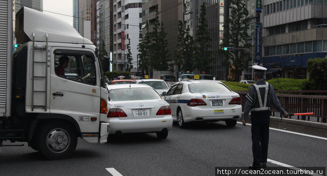 Охранник-регулировщик супермаркета перекрыл движение, чтобы выпустить грузовик… Токио, Япония