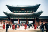 Живописные охранники и многочисленные туристы перед центральным входом в Кёнбоккун. За воротами виднеется главный павильон дворца — Кынчжончжон.