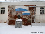 Перед проходной на фоне жизнеутверждающего панно, в снегу — бюст В. Ногина, установленный в годы Советской власти, по случаю присвоения фабрике его имени.