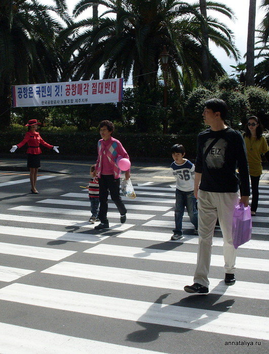 Регулировщица пропускает пешеходов на переходе к аэропорту. Чеджу, Республика Корея