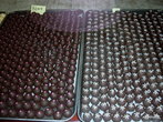 Фабрика шоколада! Вы подходите к большому застекленному цеху, где прямо перед вами, как за витриной, на огромных столах стоят противни с уложенными в ряды круглыми шоколадными конфетами.